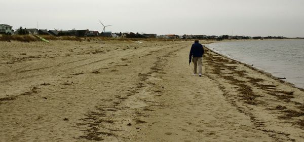 Rear view of man walking on sand