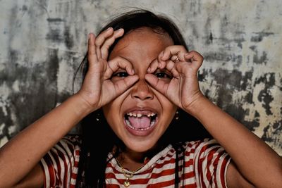 Portrait of girl making face against wall