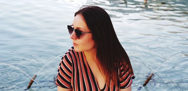 Young woman wearing sunglasses against fountain