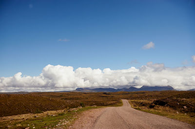 Road amidst field against sky