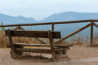 Empty bench on landscape against sky