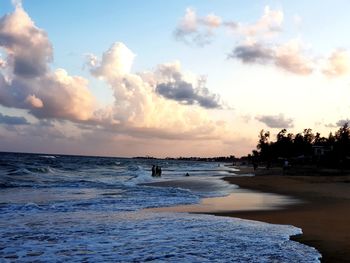 Man standing on beach against sky during sunset