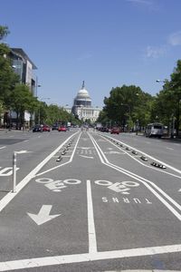 Road leading towards capitol building against sky on sunny day