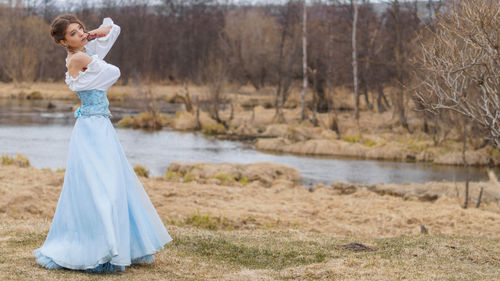 Woman in dress standing at lakeshore