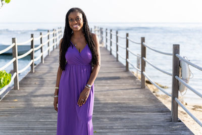 Portrait of a young woman standing on a pier against the sea