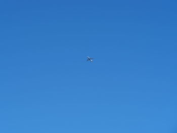 Low angle view of airplane flying in clear blue sky