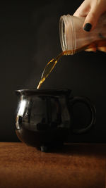 Close-up of hand holding tea cup on table