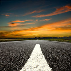 Surface level of road against sky during sunset