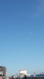 Low angle view of airplane flying against clear blue sky