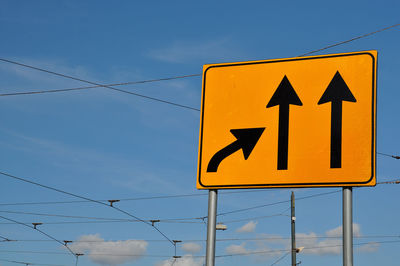 Low angle view of road sign against blue sky