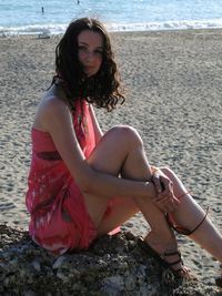 Portrait of young woman sitting on rock at beach