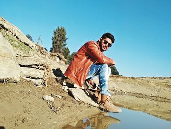 Portrait of young man standing against clear blue sky