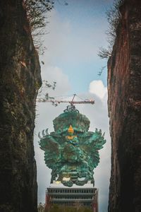 Statue of trees against cloudy sky