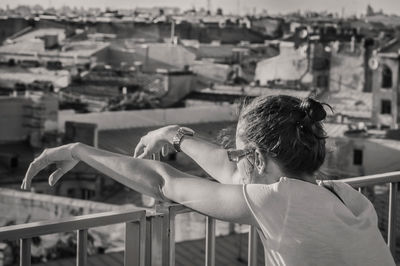 Rear view of woman standing by railing in city