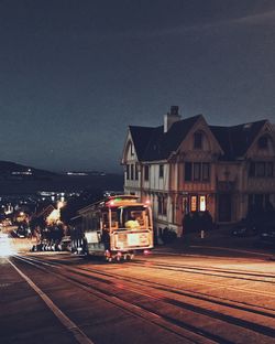 Illuminated railroad tracks against clear sky at night