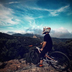 Man riding bicycle on mountain against sky