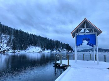 Built structure by trees against sky during winter