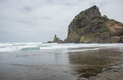 Rock formation on beach against sky