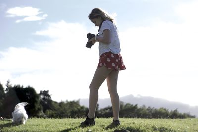 Woman with dog standing against sky