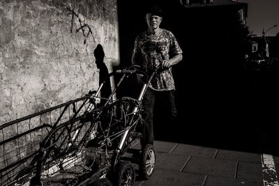 Full length of man standing on footpath against wall