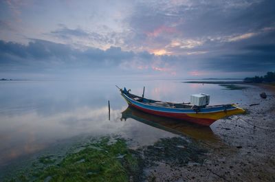 Boat moored on sea against sky during sunset