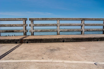 Pier on beach against blue sky