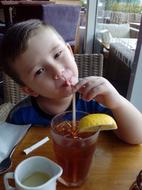 Portrait of cute boy sipping drink at restaurant