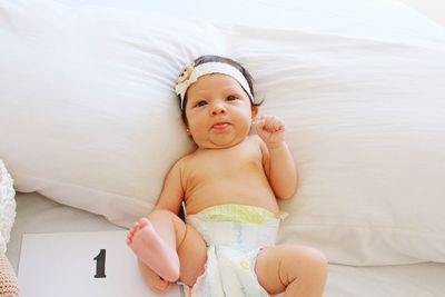 High angle portrait of cute baby girl relaxing on bed