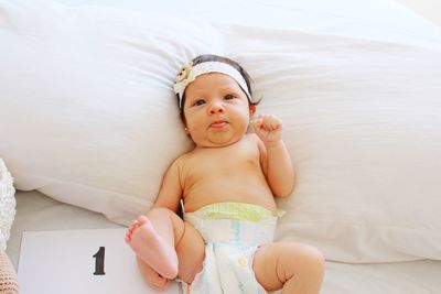 Portrait of baby girl lying on bed