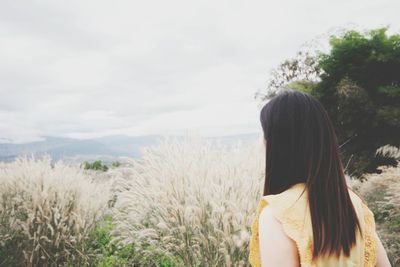 Rear view of woman standing on field against sky