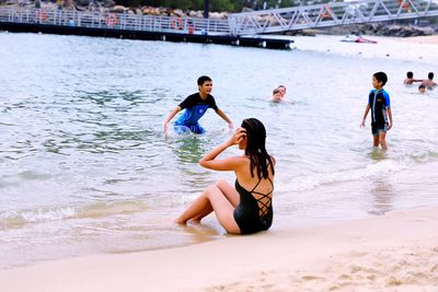 Rear view of people enjoying at beach