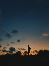 Silhouette man standing on field against sky during sunset