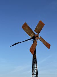 Low angle view of weather vane against blue sky