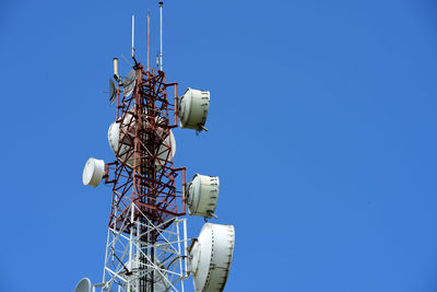 Low angle view of communications tower against clear blue sky