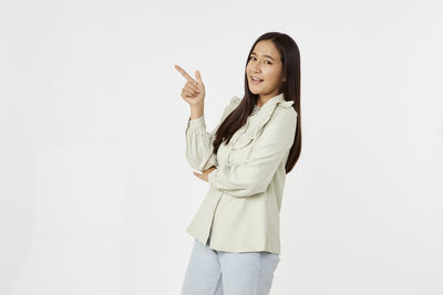 Portrait of smiling young woman standing against white background