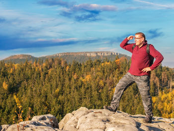 Man standing on rock against sky