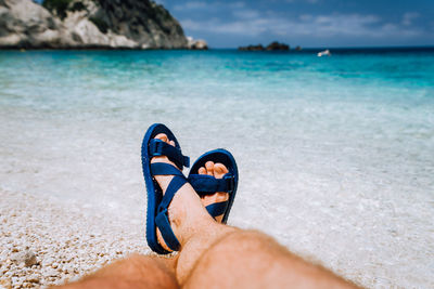 Midsection of man at beach against blue sky