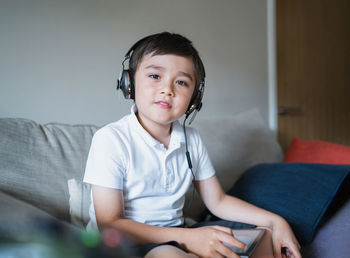 Kid wearing headphone listening to music,child boy doing homework by using digital tablet