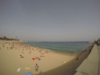 Panoramic view of people on beach against clear sky