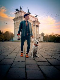 Man with dog against sky during sunset in city