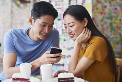 Young woman using phone while sitting on table