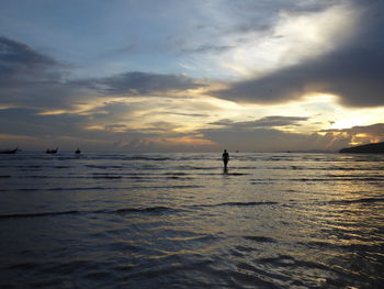 Silhouette man on beach against sky during sunset