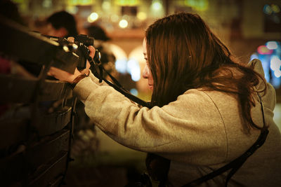 Side view of teenage girl photographing with camera