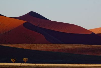 Scenic view of desert against clear sky on sunny day