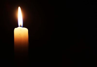 Close-up of lit candle against black background