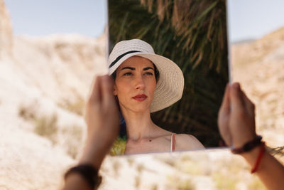 Cropped hands of woman holding mirror with reflection