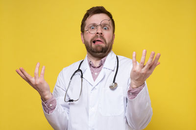 Mid adult man looking away against yellow background