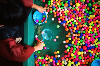 High angle view of boy collecting colorful balls floating in wading pool
