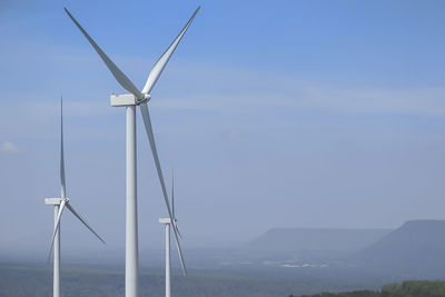 Wind turbines on landscape against sky