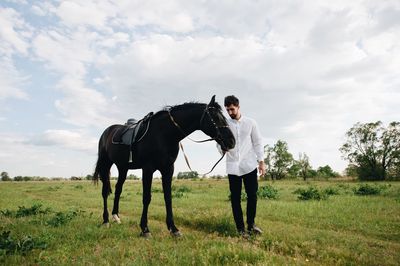 Man standing by horse on field